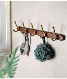 a coat rack with three coats hanging from it's hooks and two scarves