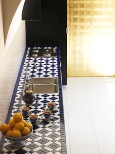 a blue and white tiled kitchen with oranges in the bowl on the counter top