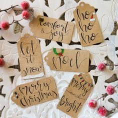 christmas tags with handwritten words on them sitting on a lace doily covered table