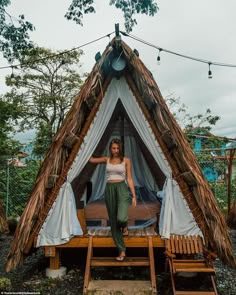 a woman standing in front of a teepee tent with curtains on the outside and inside