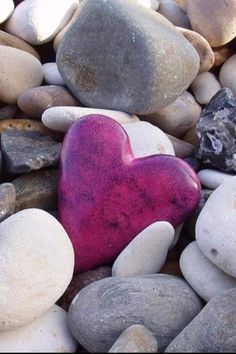 a pink heart sitting on top of some rocks