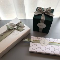 two gift boxes with bows on them sitting next to each other