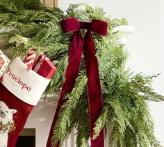 christmas stockings hanging from a mantel decorated with greenery