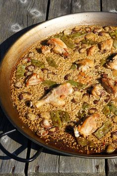 a pan filled with chicken and rice on top of a wooden table