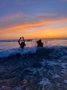 two women are in the ocean at sunset