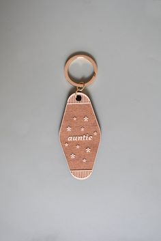 a gold keychain with an animal print on the front and bottom, hanging from a metal hook