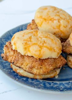 three biscuits are stacked on top of each other on a blue and white plate, with another biscuit in the background