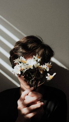 a person holding flowers in front of their face