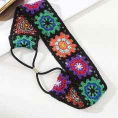 a crocheted black and multicolored headband laying on top of a table