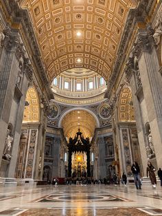 the inside of a building with people walking around and statues on the ground in front of it