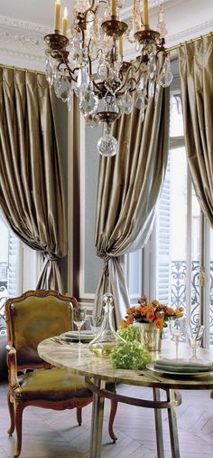 an elegant dining room with chandelier, chairs and table in front of large windows