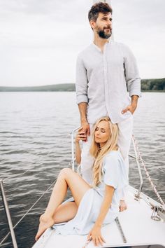 a man standing on the back of a boat next to a blonde woman sitting on top of it