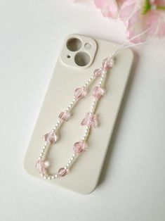 Add a touch of whimsy to your phone with our charming beaded phone strap. Crafted with delicate small pearls and accented with adorable pink butterfly and heart beads, this phone charm is the perfect blend of elegance and fun. Designed to be both stylish and functional, it can be used as a phone chain, keychain, or bracelet. This delightful accessory is ideal for adding a unique flair to your phone and makes a thoughtful gift for any occasion. Iphone Keychain Beads, Pink Phone Charm, Pearl Phone Charm, Phone Keychain, Homemade Necklaces, Strap Phone, Butterfly Heart, Jewerly Beads, Phone Wristlet