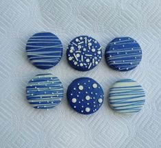 four blue and white decorated buttons sitting on top of a sheet with polka dot designs