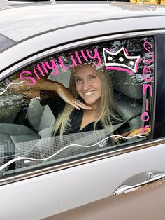 a woman is sitting in her car smiling for the camera