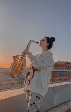 a woman standing on top of a roof playing a saxophone