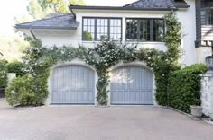 a large white house with two garage doors and ivy growing on the side of it