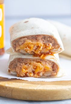 two burritos sitting on top of a cutting board