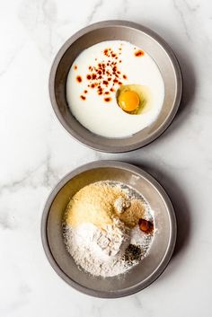 two bowls filled with different types of food on top of a white marble countertop