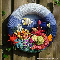 a crocheted wreath with sea animals and fish in it on a wooden fence