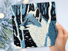 a hand holding up a card with an image of a wolf in the woods