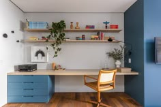 a room with a desk, shelves and a chair in the corner next to it