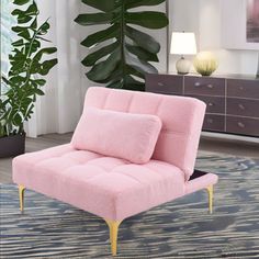 a pink chair sitting on top of a rug in front of a potted plant