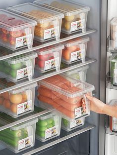 a woman is reaching into an open refrigerator with lots of food in plastic bins