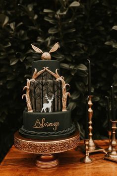 a three tiered cake decorated with deer and antlers is on a table next to candles