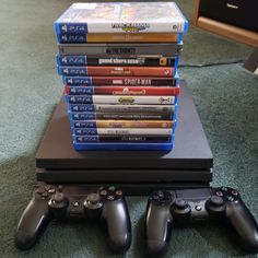 a stack of video games sitting on top of a table next to a pile of controllers