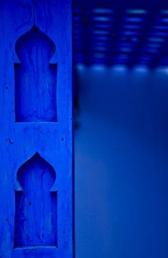 a blue door with an intricate design on the front and back sides is illuminated by light from below