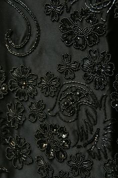 the back of a black dress with flowers on it