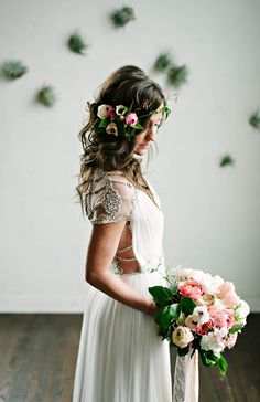 a woman in a white dress holding a bouquet of flowers and wearing a flower crown