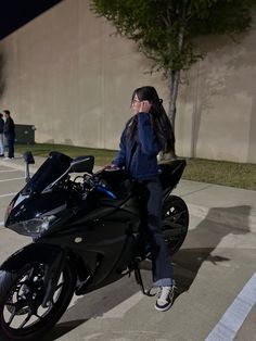 a woman sitting on top of a black motorcycle