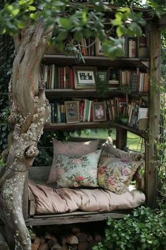 a wooden bench sitting in the middle of a garden next to a book shelf filled with books