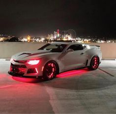 a white sports car with red lights on it's side in front of a city skyline