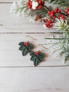 holly and berry earrings on white wooden background