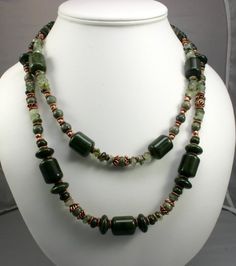 This wonderful piece of Jill's Jewelry is the perfect accessory for you.  The necklace is made from various types of green stones, green jasper, serpentine and prehenite.  The color of those green stones is really brought out by lovely copper highlights.  The copper bead caps, beads and clasp really make the green shades stand out.  The necklace also offers unusual shapes to attract the eye.  You'll get nothing but compliments when you wear this necklace.  The coordinating earrings shown above a Green Moss Agate Round Bead Necklaces, Green Moss Agate Round Bead Necklace, Green Jasper Spiritual Jewelry, Green Jade Gemstone Beaded Necklace, Green Jade Beaded Necklaces With Natural Stones, Green Jasper Jewelry With Natural Stones, Handmade Green Jasper Jewelry, Green Jade Necklace With Natural Stones, Elegant Green Jade Necklace With Natural Stones