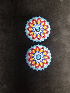 two beaded buttons sitting on top of a black surface