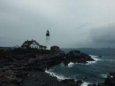 a light house sitting on top of a rocky cliff next to the ocean under a cloudy sky