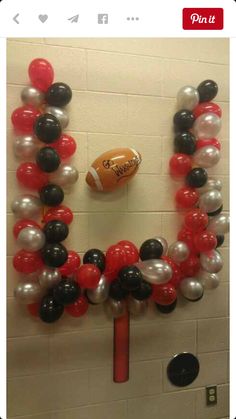 an image of balloons and footballs in the shape of a wreath on a wall