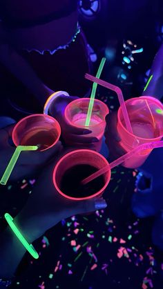 neon colored cups and straws are being held by two hands