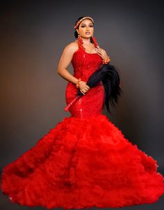 a woman in a red dress with feathers on her head and hands behind her back