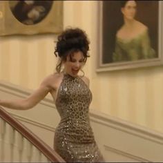 a woman in a leopard print dress is walking down the stairs with her hand on her hip