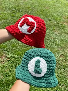 two crocheted hats with the letter q on them are held by someone's hand