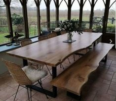 a wooden table and chairs in a room with large glass windows on the side wall