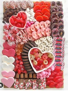 an assortment of heart shaped candies and chocolates arranged on a board with paper hearts