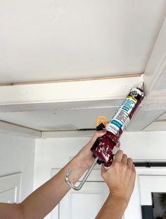 a person is painting the ceiling with red and white paint on it, while holding a spray bottle in their hand