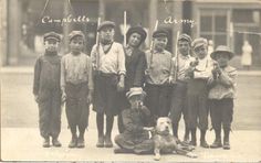 an old black and white photo of children with a dog sitting on the ground in front of them