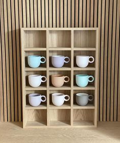 a wooden shelf filled with lots of different colored cups